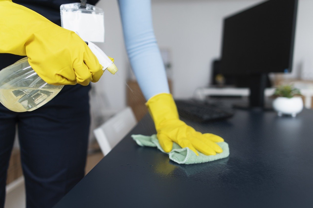 Professional office cleaner in front of desk